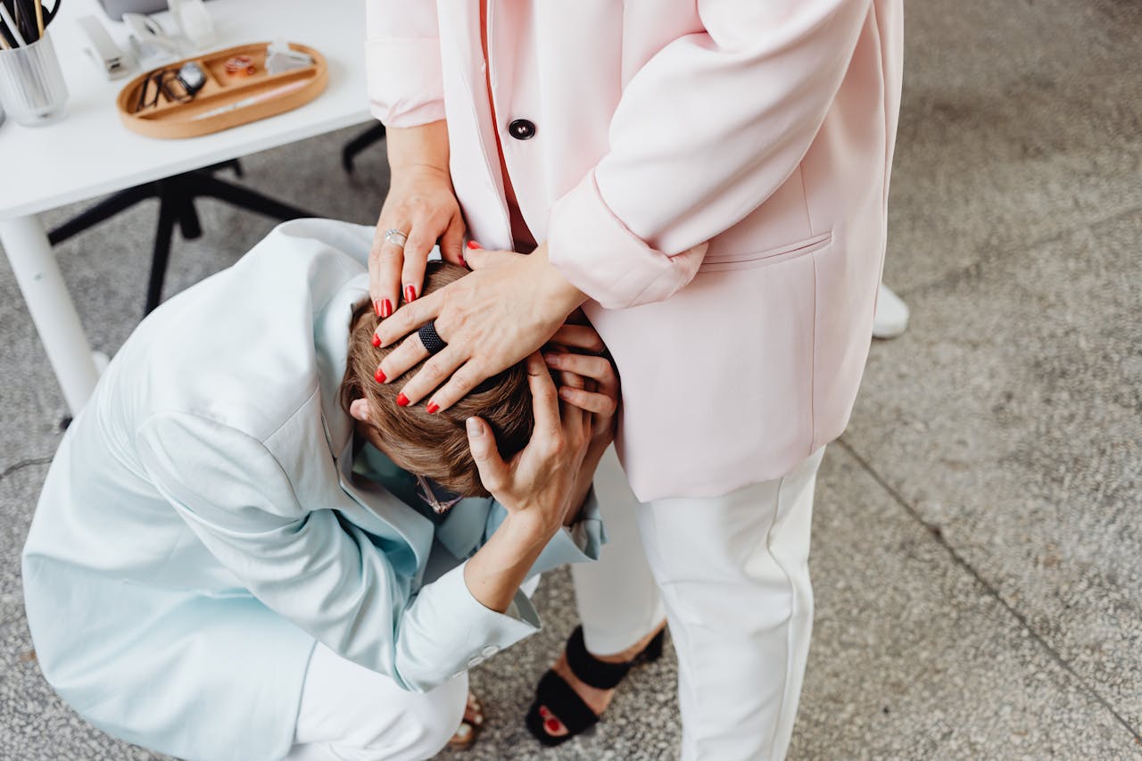 Two women in business attire providing emotional support indoors.